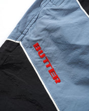 Afbeelding in Gallery-weergave laden, BUTTER GOODS X UMBRO - &quot;DIAMOND&quot; TRACKSUIT PANTS (BLACK/SLATE)
